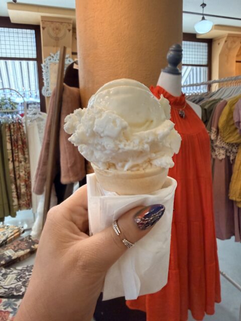 caucasian hand holding an ice cream cone inside of Chandelier Boutique