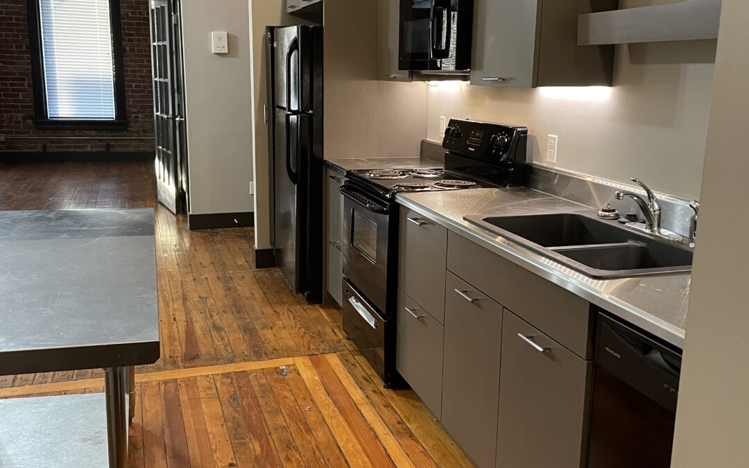 a galley kitchen with hardwood floors and stainless steel appliances in the Eureka Flats apartments